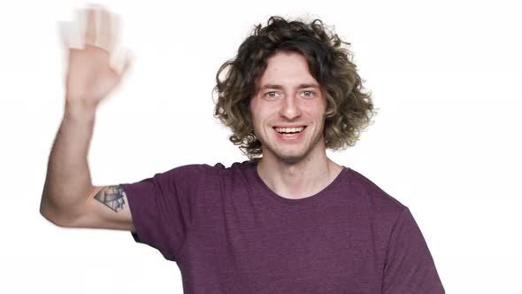 Portrait of Positive Hairy Man in Casual Tshirt Smiling and Greeting with Waving Hand Isolated Over