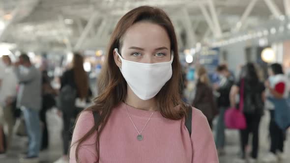 Portrait of a Woman in Medical Mask Looking Straight at Camera in Airport Terminal Preventing