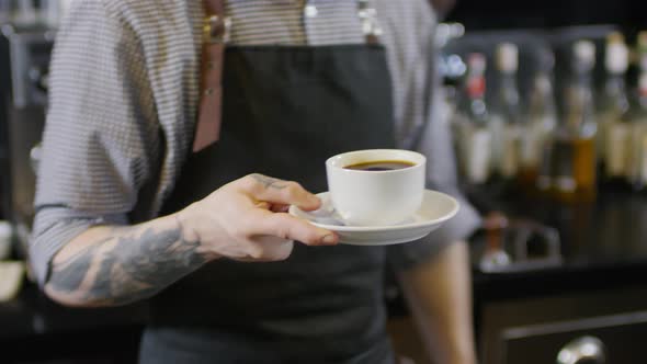 Tattooed Male Barista Posing with Cup of Americano