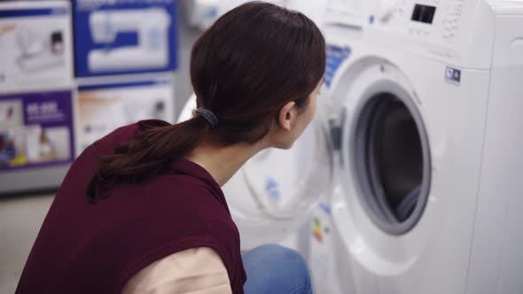Young Brunette Girl Opens a Washing Mashine Door Spins the Cylinder Inside and Pulls Out Detergent