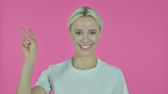 Victory Sign By Young Woman on Pink Background