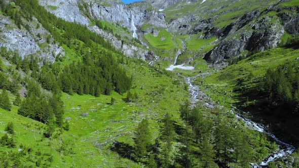 Aerial: drone flying over scenic waterfall and mountain stream on the italian Alps