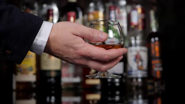 Closeup of a Businessman Holding a Glass of Cognac in a Bar