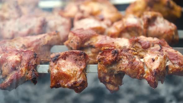 Shashlik or shish kebab preparing on barbecue grill over hot charcoal. Grilled pieces of pork meat