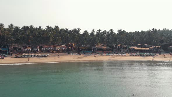 Beach chairs resting in Palolem Beach near turquoise ocean shore