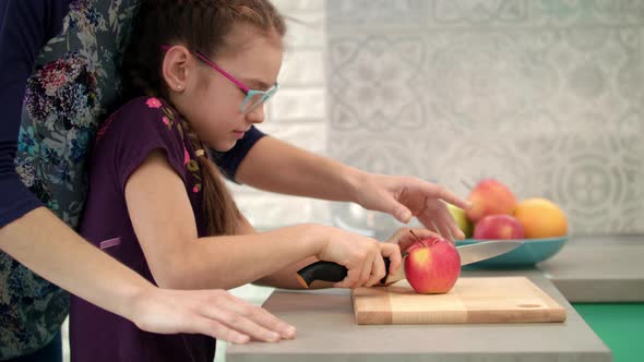 Mother Help Daughter To Cut Apple on Cutting Board