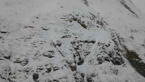 Snowy Steep Surface Of Otertinden Mountain In Northern Norway - aerial tilt up shot