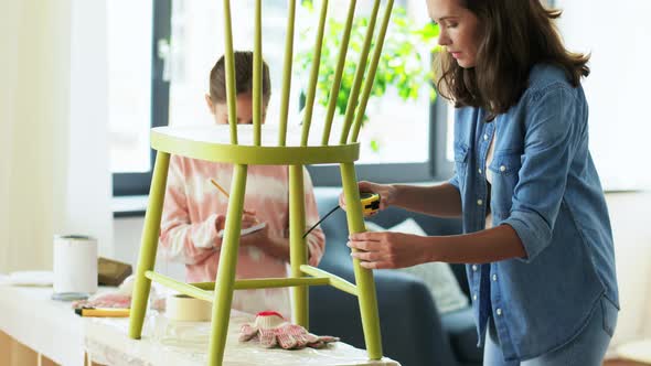 Mother and Daughter with Ruler Measuring Old Chair