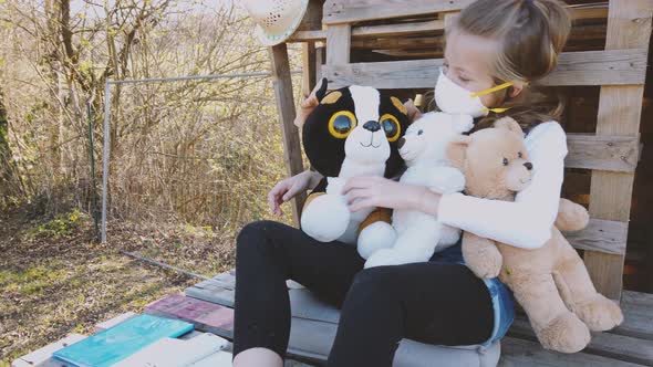 Slow motion shot of girl with mask playing with her teddies in garden