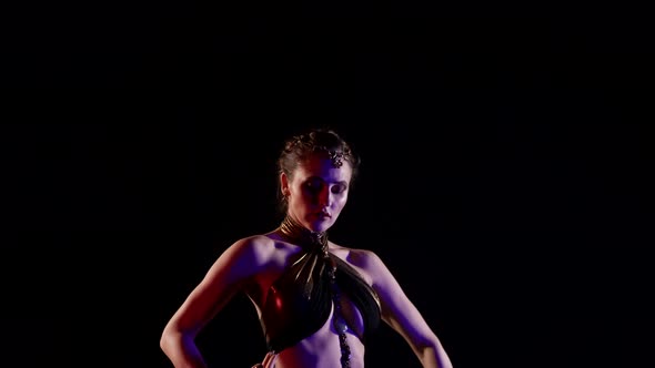 A Beautiful Woman Who Dances an Oriental Belly Dance on a Black Background Makes Movements with Her