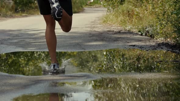 Runner Close Up Of Legs. Runner Muscle Legs Front View. Close Up Shot Of A Male Run. Puddle Splash.