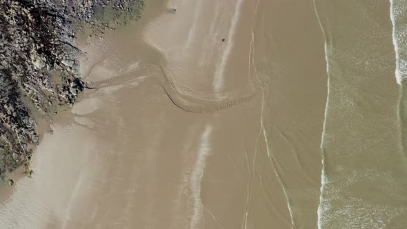 Aerial bird's eye drone view over  Irish beach at golden hour.