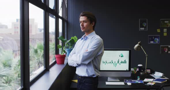 Caucasian businessman standing looking out of window in modern office