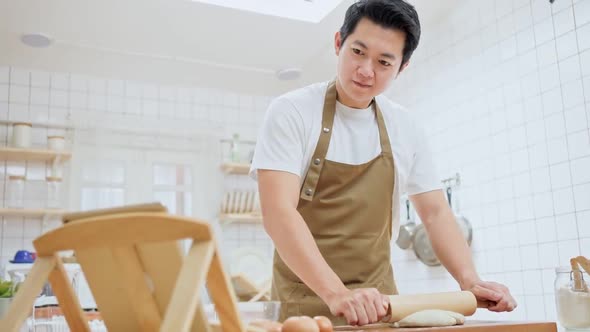 Young handsome male kneads yeast dough with his hands, learn how to make bread by using tablet.