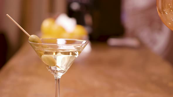 Green Olives in a Glass of Martini on a Bar Counter