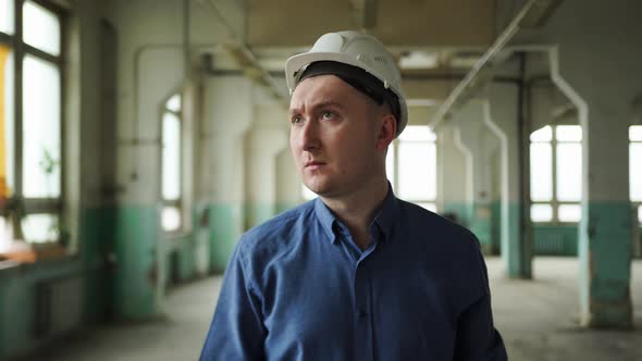 Inspector in Helmet Walks Along the Corridor of an Old Building Looks Around