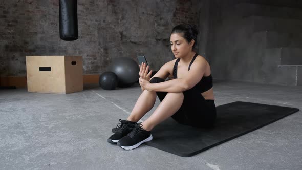 A young Indian Woman Dressed in Sportswear Black Leggings and a Top Is sitting Tired