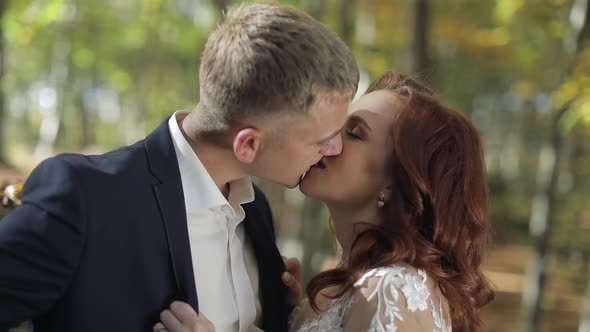 Groom with Bride in the Forest Park. Wedding Couple. Making a Kiss