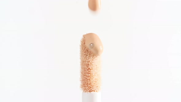 Makeup Liquid Beige Foundation Pouring on Makeup Brush Closeup