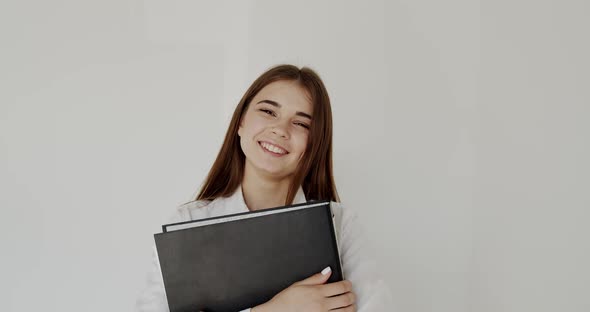 Office Girl with Folder in Hands Looks and Smiles at Camera on White Background