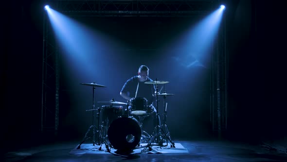 Silhouette Drummer Playing on Drum Kit on Stage in a Dark Studio with Smoke and Neon Lighting