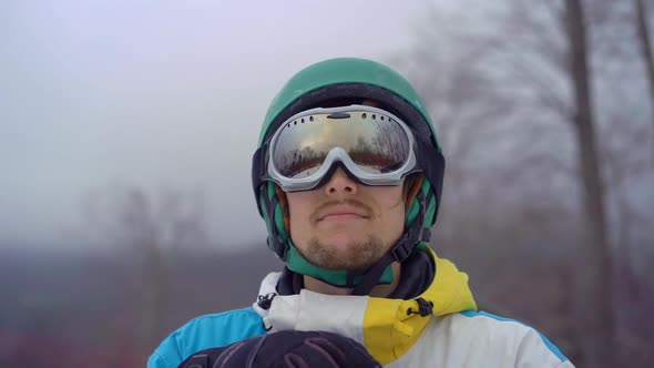 Closeup Shot of a Young Man Wearing a Snow Googles Looks at a Hillside. Winter Holidays Concept