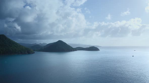 Aerial camera approaches the hilly coast of the blue sea with yachts (Saint Lucia)