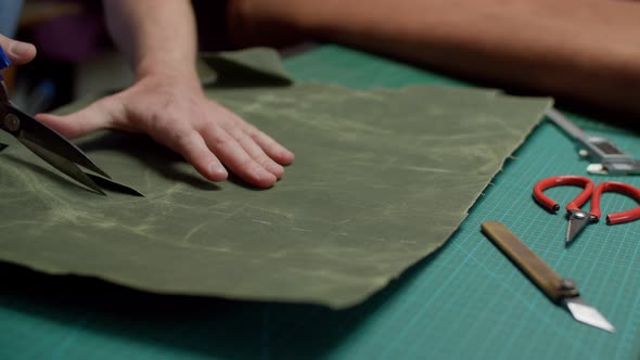 Tailor Cutting Canvas Fabric with Scissors Along Cut Lines on Work Table Indoors