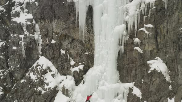 Breathtaking aerial view of ice climber scaling frozen cascade Mount Kineo 4K