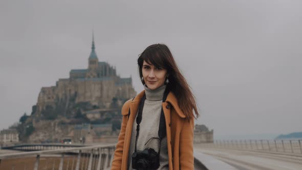 Portrait of Beautiful Elegant Brunette Blogger Woman Smiling at Camera at Epic Mont Saint Michel