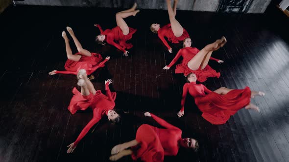 Seven Female Dancers Are Lying on a Floor in Round Figure, Moving and Standing Up Top View on Their