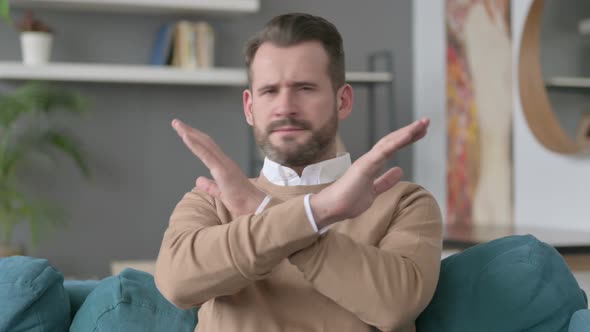 Portrait of Man Showing No Sign By Arm Gesture at Home