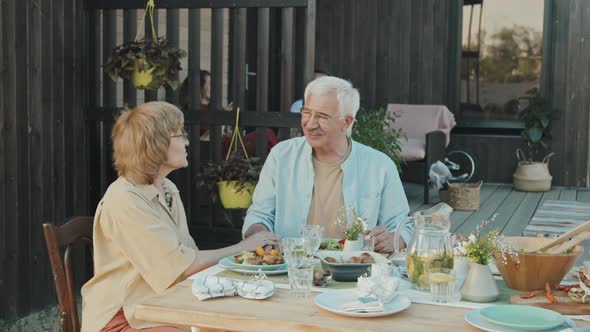 Senior Spouses Talking at Table Outdoors