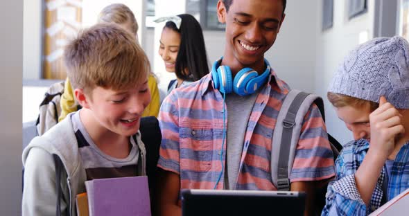 Students standing with notebook and digital tablet in corridor