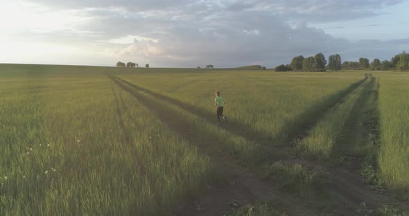 Sporty Child Runs Through a Green Wheat Field