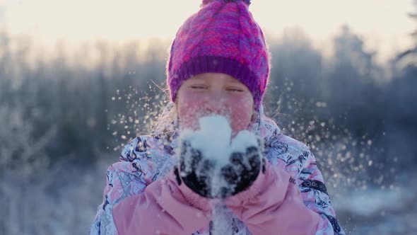 Portrait female blowing snowflakes holding in hands at winter outdoors