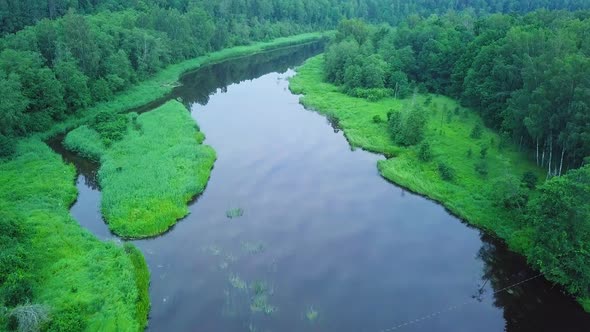 Aerial birdseye view of a Venta river (Latvia) on a sunny summer day, lush green trees and meadows,
