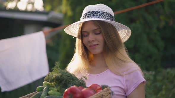 Happy Young Caucasian Woman Smelling Harvest in Basket on Summer Autumn Day Smiling