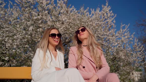 Two females persons sitting talking outside. Young adult women spending time together at park