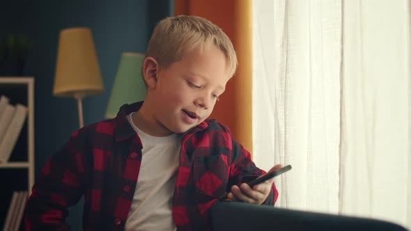 Cute Little Kid is Sitting on a Couch an Speaks Via Video Link