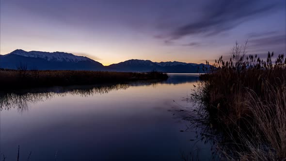 Night-to-day sunrise timelapse with stunning light changes at a river flowing gently into a lake