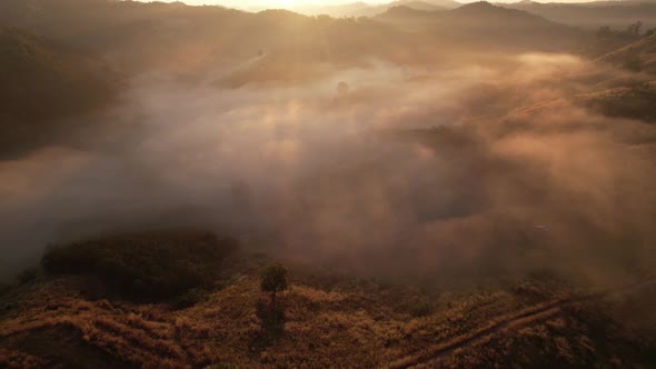 4K aerial view over a misty mountainous area. The great golden sun in the morning