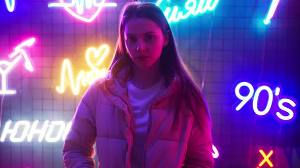 Young Woman Standing Against Wall with Neon Lights