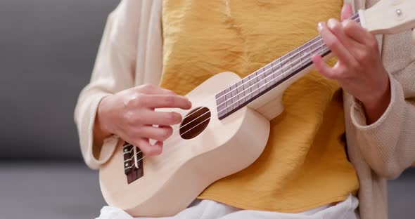 Girl playing ukulele at home