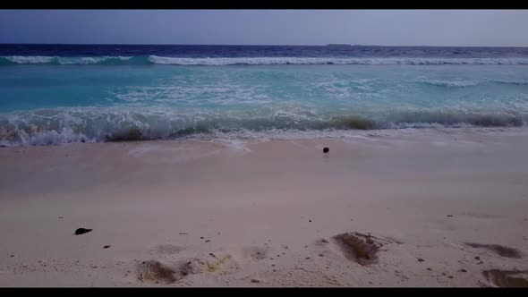 Aerial drone shot seascape of tranquil tourist beach holiday by blue sea with white sandy background