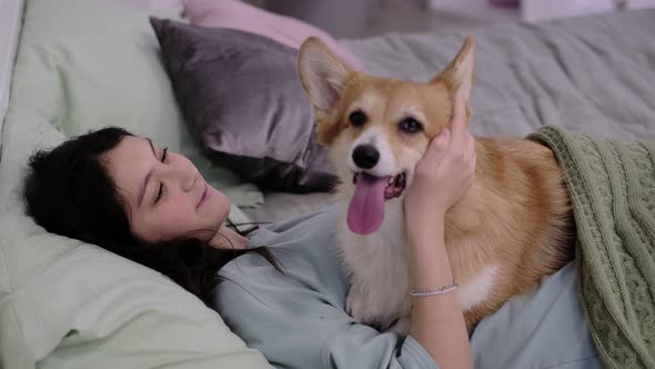 Young Teenage Girl Relaxing in Bed with Her Dog