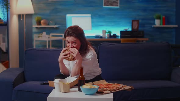 Young Woman Eating Hamburger and Fries Laughing