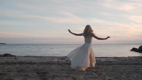 Ballerina in a Flowing Dress Dancing By the Sea at Sunset