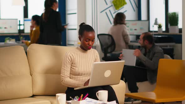 African American Lady Writing on Laptop Looking at Camera Smiling