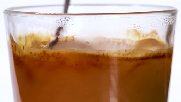 Grains of instant coffe falling into a glass of hot water and dissolving, macro shot close up view.